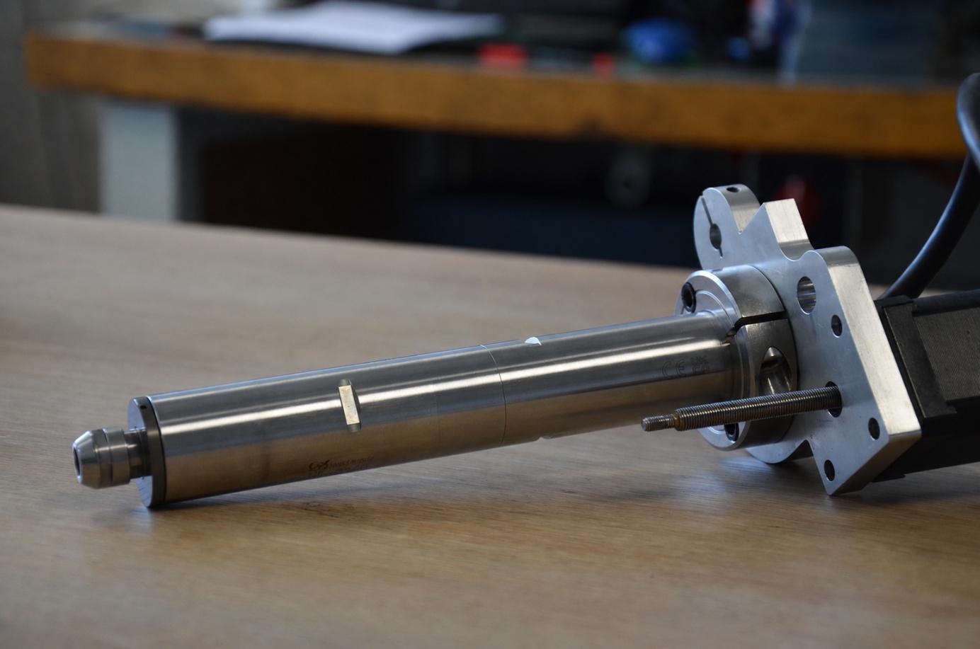 Ensemble broche-moteur posé sur une surface en bois.
