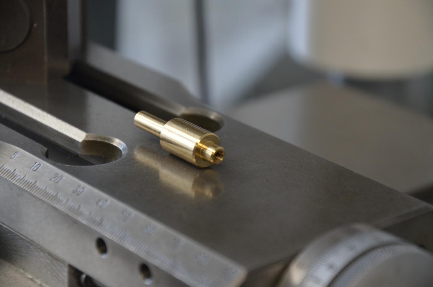 Pièce en laiton usinée posée sur une machine-outil.
