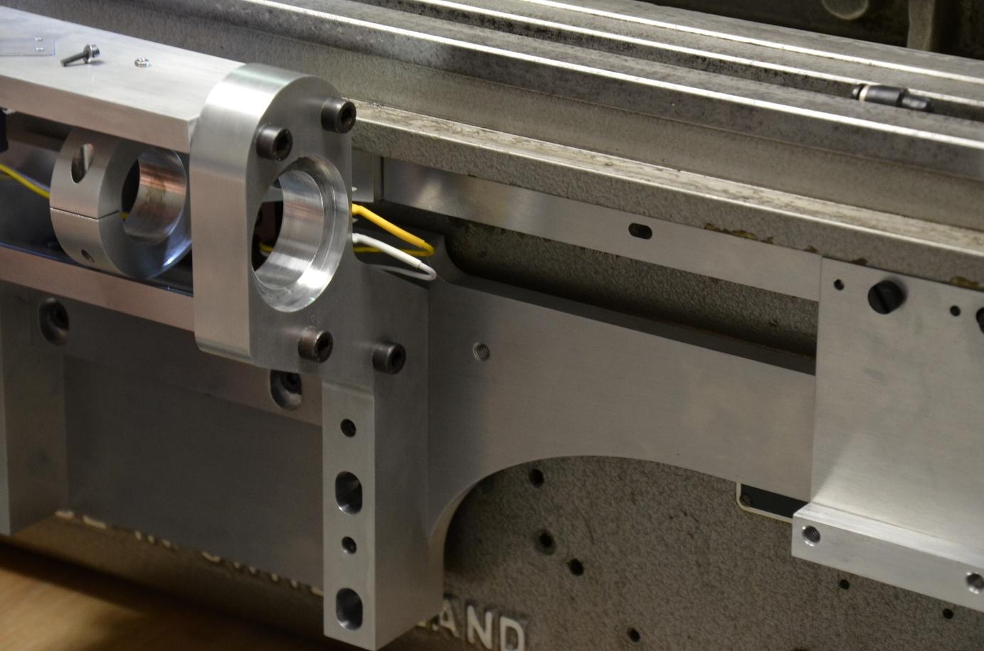 Mécanisme en aluminium monté sur une base en fonte grise.